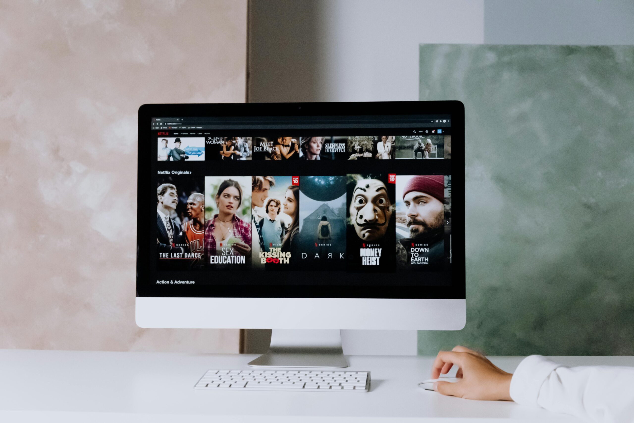 A modern workspace featuring a desktop screen displaying popular streaming series on Netflix.